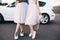 Attractive legs of fashion models in tulle skirts and sneakers on white car background.