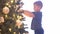Attractive little boy decorating Christmas tree with balls and lights. Kid preparing for the New Year at home.