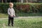 An attractive little boy stands next to a swing with chains in a city park, a child getting ready to swing. Horizontal photo