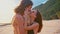 Attractive, in love, beautiful young travel couple enjoying sunset on the beach kissing and hugging in slow motion. Sea