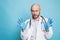 Attractive man bald bearded doctor in rubber medical gloves looking at camera isolated on blue background