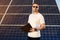 Attractive man with a folder in his hands on background of solar panels at warm day