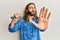 Attractive man with long hair and beard singing song using microphone with open hand doing stop sign with serious and confident