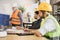 Attractive man in reflective vest sitting at table with males architects in uniform and helmets