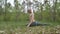 Attractive man stretches the legs and doing a sporty exercises in forest