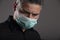 Attractive man with surgical protection mask on gray background. Coronavirus concept. Protect your health