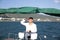 Attractive man in white stands at the helm of a yacht at sea and looks at the horizon with his hand raised Sailing, tourism travel