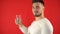 Attractive man in a white T-shirt holds in his hand a glass of water on a red background. Healthy lifestyle concept