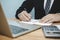 Attractive manager businessman in black suit working, writing on document report on desk