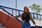 Attractive mature woman in black transparent shirt and jeans, leaning on a railing, smiling very happy, independent and empowered