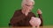 Attractive mature woman putting dollar into piggy bank on greenscreen