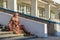 Attractive middle-aged woman wearing stylish coat and shoes sitting with bag on stairs step of office building in early spring at