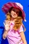 Attractive model Barbie style girl wearing sunglasses, pink tee-shirt and shorts with long hair on blue backdrop