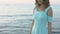 Attractive model dressed in a blue dress posing near the sea