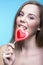 Attractive model lick the lollipop in the shape of a heart