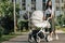 attractive mother walking with baby stroller on street