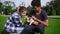 Attractive multiethnic couple sitting on the green grass in park enjoying the day while holding cute little jack russell