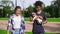 Attractive multiethnic couple walking together in park enjoying the day. African boy is holding cute little jack russell