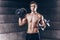 Attractive muscular man is posing with dumbbell. Fitness instructor