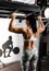 Attractive muscular woman, holding on pull ups bar