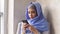 Attractive muslim girl in hijab uses smartphone in interior of expensive restaurant