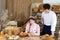 An attractive new saleswoman describes wooden plates with prices for individual types of bread under the supervision of