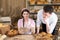 An attractive new saleswoman describes wooden plates with prices for individual types of bread under the supervision of