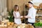 An attractive new saleswoman describes wooden plates with prices for individual types of bread under the supervision of