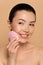 Attractive nude asian girl using pink silicone cleansing facial