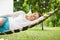 Attractive older woman lying on hammock in garden