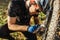 Attractive outdoor close up shot of concentrated young rider in protective gear sitting on grass in front of his broken bicycle,