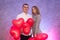 Attractive pair with red air balloons smiling in studio. Couple in love