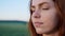 Attractive pensive girl having brown eyes standing in the field outdoor.