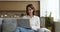 Attractive pensive woman sits on sofa working online using laptop
