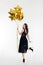 Attractive playful happy woman looking back and holding golden balloons