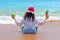 Attractive plus size women with tropical fruits in hands in Santa`s hat is sitting on the ocean. She did not have time to lose