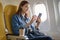 Attractive portrait of Asian woman sitting at window seat in economy class using mobile phone during plane flight