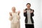 Attractive positive seniors couple in hoodies, old man and woman doing rock and roll gesture and looking at the camera