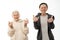 Attractive positive seniors couple in hoodies, old man and woman doing rock and roll gesture and looking at the camera