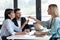 Attractive real-estate agent giving house keys to young couple after signing agreement contract in the office