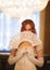 Attractive red haired woman in vintage 18 centuries dresses use fan in luxury ballroom
