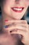 Attractive red lip stick: Blonde young woman with colorful nail polish is looking herself in the mirror. Cut out of the face