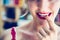 Attractive red lip stick: Blonde young woman with colorful nail polish is looking herself in the mirror. Cut out of the face