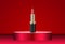 Attractive red lipstick product on round premium podium. Isolated on red background. Makeup container mockup