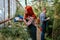 Attractive redhead gardener lady and her colleague man working together in a large greenhouse they analyzing the