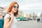 Attractive redhead smiling girl in sunglasses in casual clothes with backpack on street in city