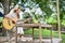 Attractive and relaxed young Asian female camper singing her song and playing guitar