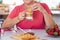 Attractive retired senior woman enjoying breakfast at home with croissant and cappuccino. Strawberries on the table