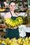 attractive salesgirl proposing fresh bananas in supermarket