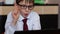 Attractive schoolboy 7 years old in glasses is studying online while at home in front of a gadget. The child emotionally performs